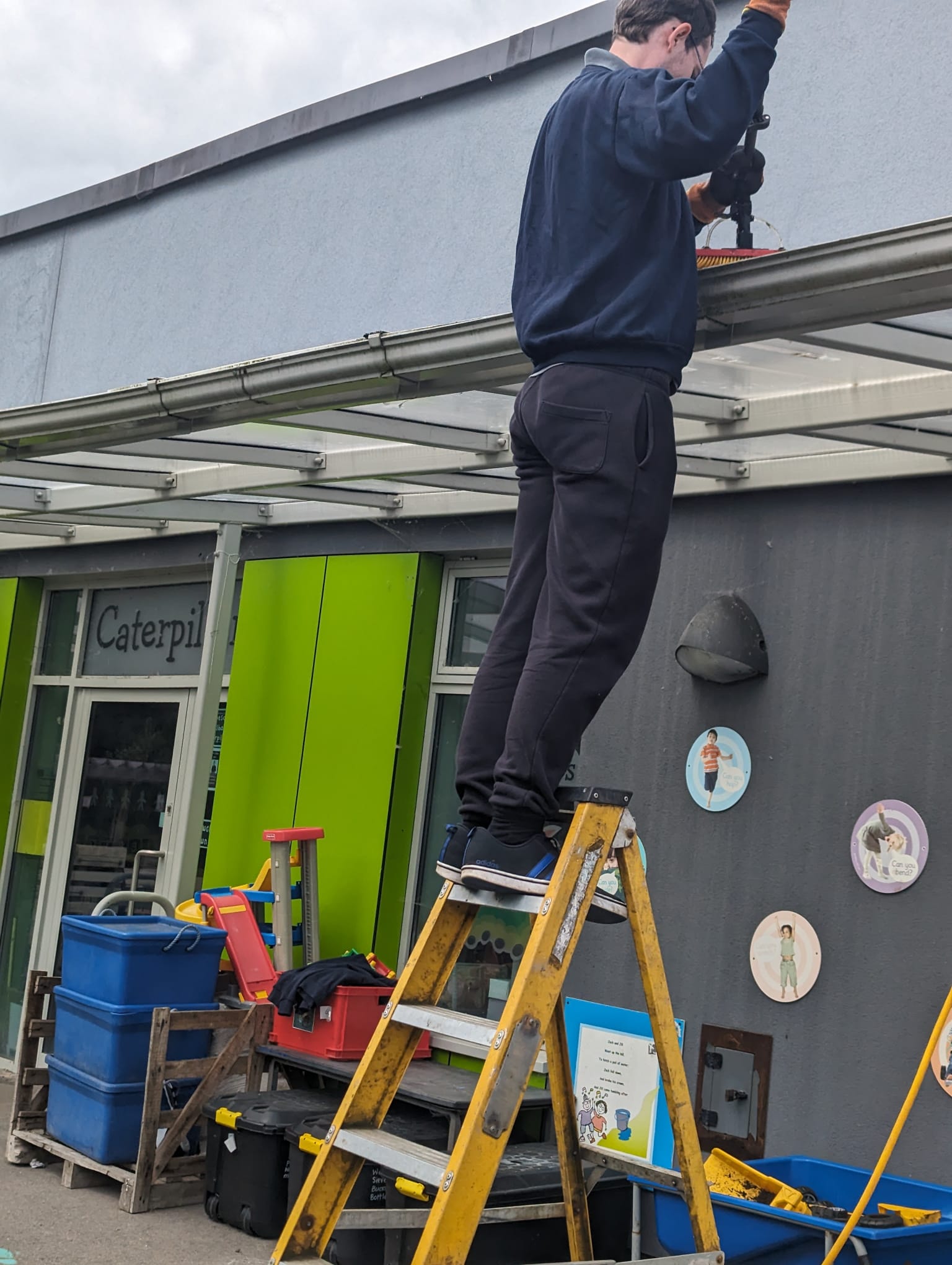 Operative on a ladder carrying out gutter cleaning at height