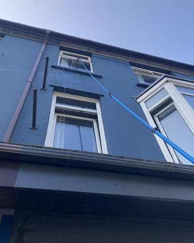 Upper-storey house windows being cleaned with a water-fed pole